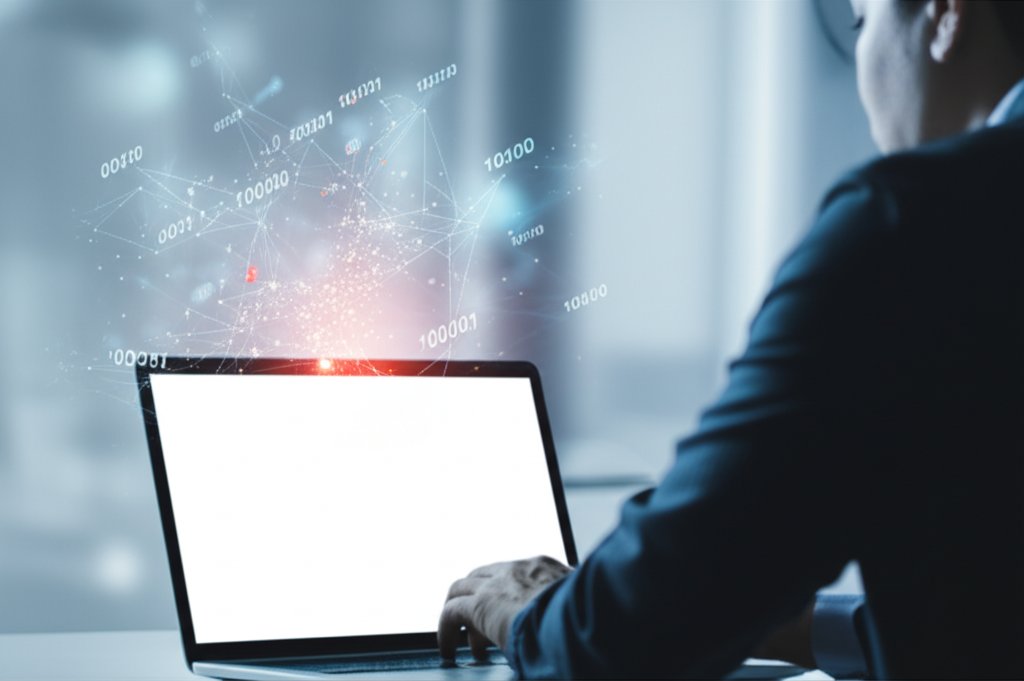 Focused person at laptop, digital patterns on screen hint at AI cyber threats. Clean, modern tech environment.